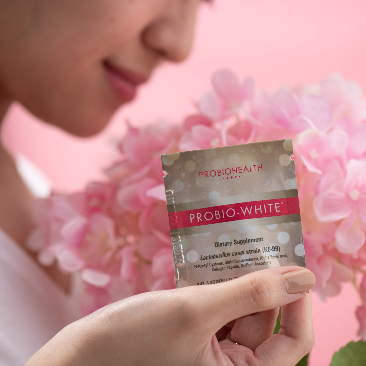 A model holding a packet of Probio-White, with pink background.