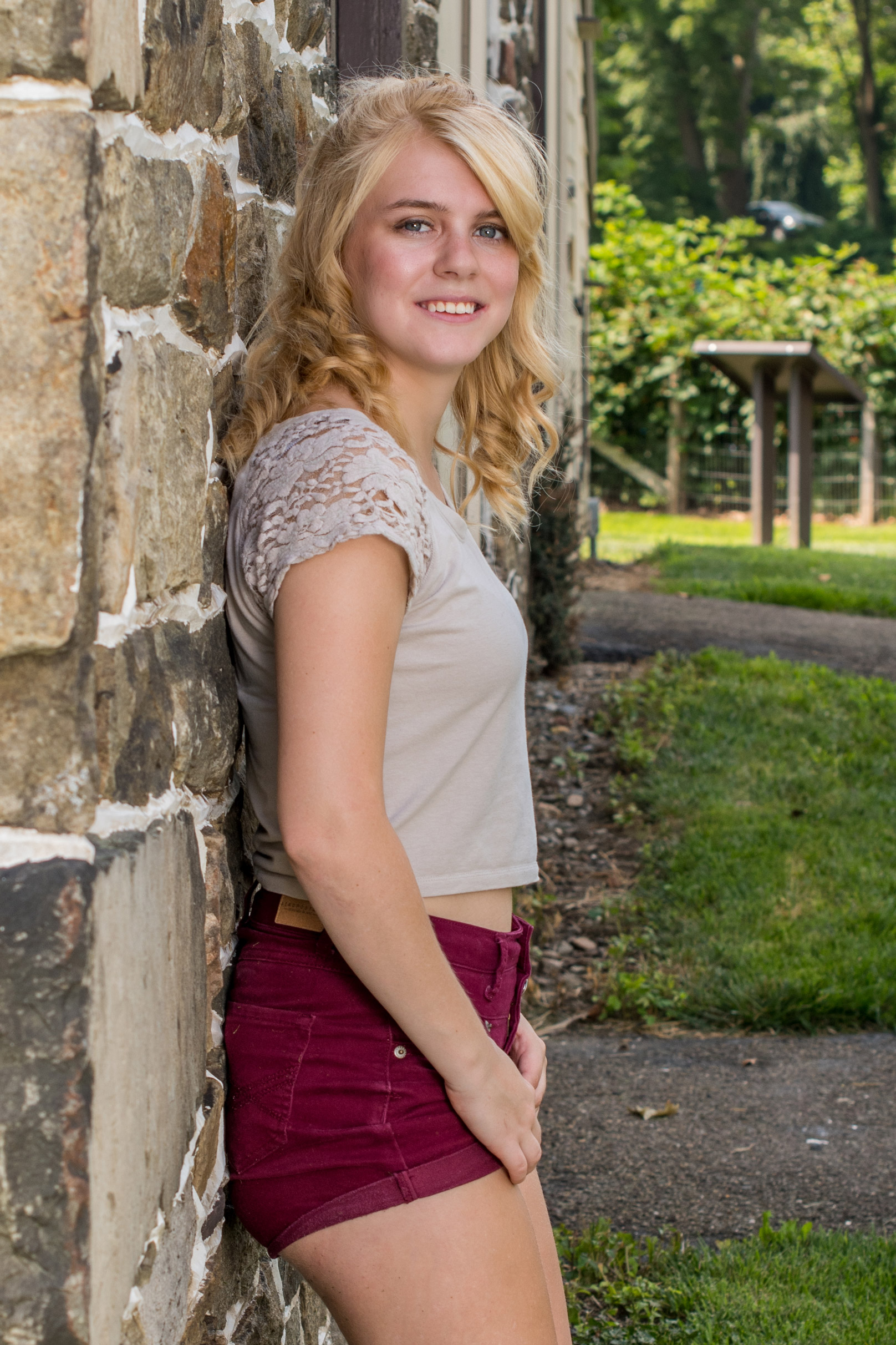 Picture of a beautiful smiling lady, leaning on a brick wall